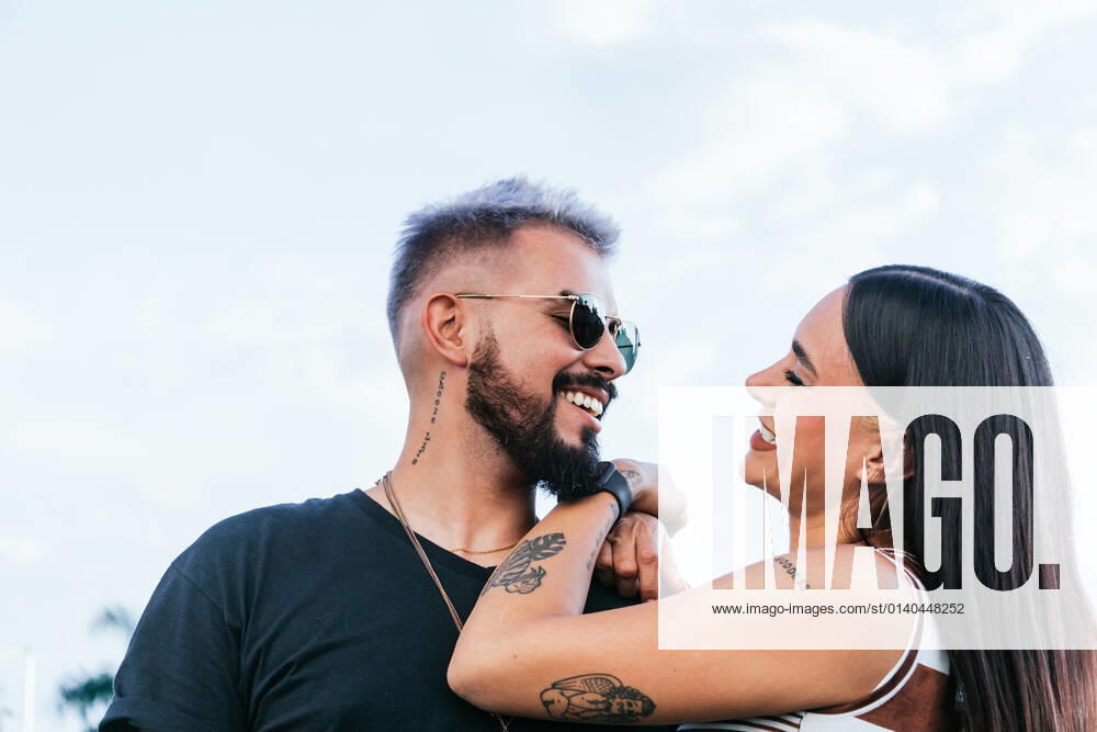 Happy female with black hair in casual clothes embracing cheerful boyfriend in sunglasses while laughing on street in daytime JoseDeJesusSaldana_Street_13.jpg