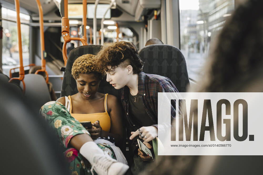 IMAGO Creative: Pride Month 2022, Engagement der Jugendlichen Teenage boy looking at young non-binary woman using smart phone in bus Sweden, Malmo, model released
