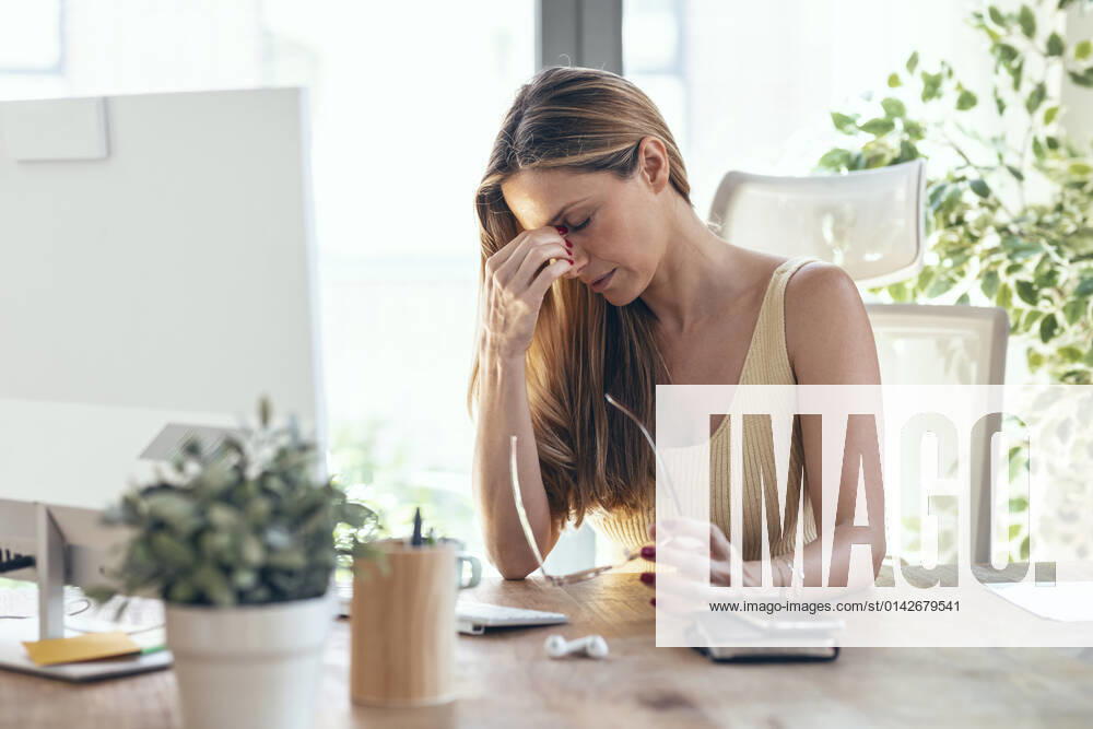 Tired businesswoman sitting at desk in home office model released property released, JSRF01673
