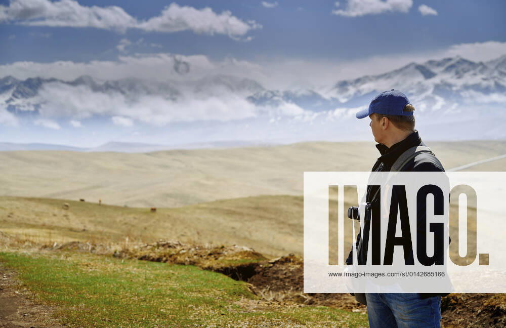 Man with camera looking at mountains model released, AZF00385