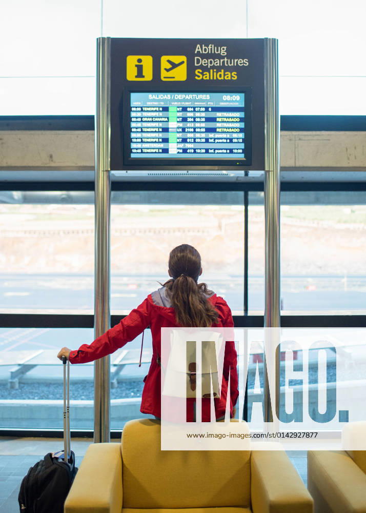Back view of anonymous female tourist with backpack and suitcase sitting on armchair near signboard with flight schedule in airport GabrielTrujillo_La PalmaAirport_14.jpg