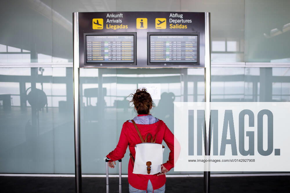 Back view of anonymous female tourist with backpack and suitcase standing near signboard with flight schedule in airport GabrielTrujillo_La PalmaAirport_33.jpg
