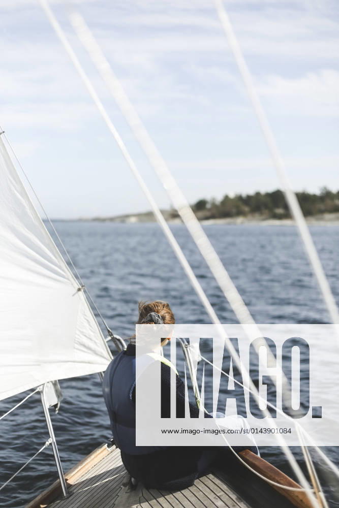 IMAGO Creative, Jahreszeit Sommer, Sommerferien Woman sitting in sailboat on sunny day Sweden, Stockholm archipelago, model released