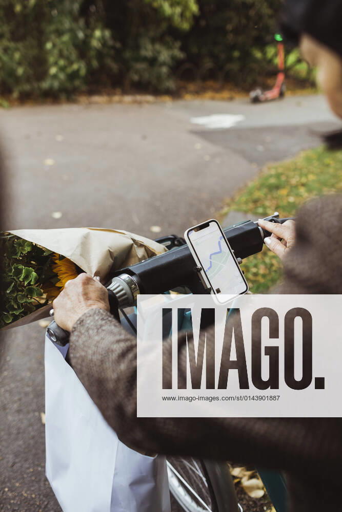 IMAGO Creative: Jahreszeit Frühling, Picknick IMAGO Creative: Landleben - Alfresco, Draußen Cropped image of senior woman cycling electric bicycle on street Sweden, Stockholm, model released
