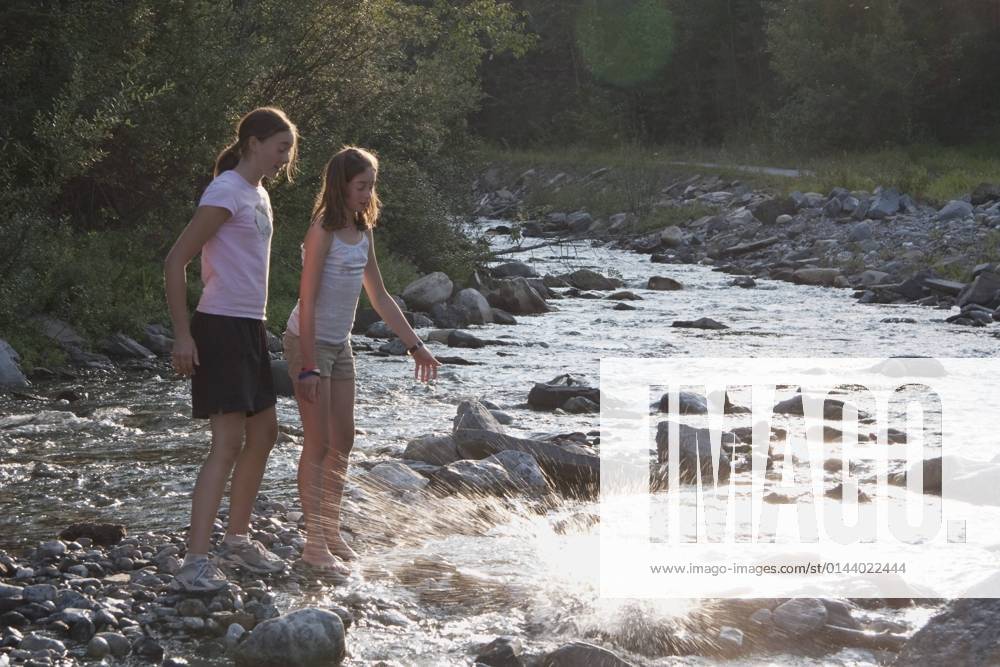 IMAGO Creative, Jahreszeit Sommer, Sommerferien Kananaskis Country, Alberta, Canada; Two Girls Throwing Rocks Into The River