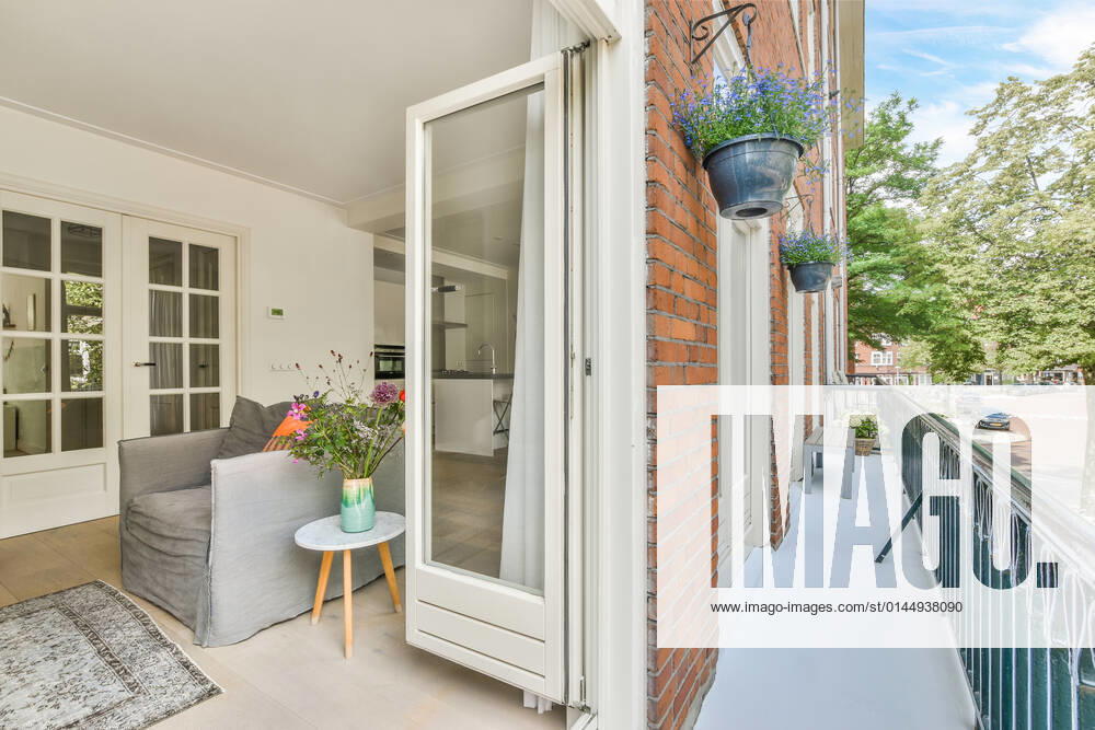 Living room with armchair and flowers near opened balcony door with metal fence and brick wall of building located on street CasaMedia_Waalstraat52-1_9.jpg