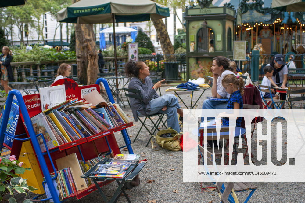People enjoying in Bryant Park a City park in Mid-town Manhattan, New York City , NY ,USA Visitors browse the selection of books on carts at the Reading Room, an open air library in New York City s Bryant Park New York New York USA