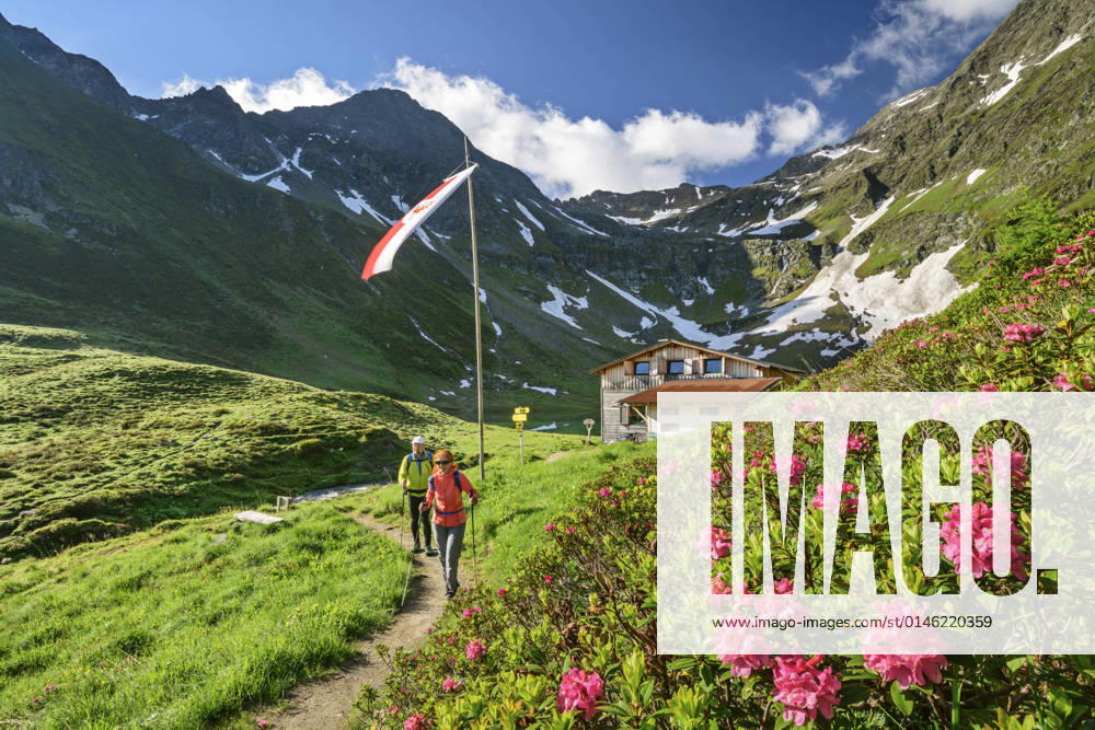 Man and woman hiking in Virgental during spring with Bergerseehutte in background model released, ANSF00090