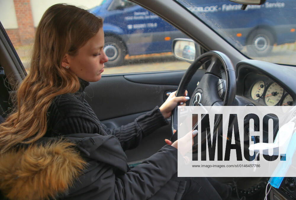 Junge frau fährt auto und schaut dabei auf ihr handy junge frau fährt auto und schaut dabei auf ihr handy
