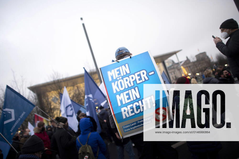 Protest AfD - Gegen Impfplicht DEU, Deutschland, Germany, Berlin, 11.12.2021 Demonstrant mit Plakat Mein Koerper Mein Recht Freies Land Freie Impfentscheidung vor Transparent Die Jugend Steht Auf Telegram Impfstreik auf einer Kundgebung und Demonstration der Jungen Alternative JA, die Jugendorganisation‹ der rechtsextremen Partei Alternative fuer Deutschland AfD gegen eine Impfpflicht und die Coronapolitik der Bundesregierung unter dem Motto Impfstreik Deutschland im Regierungsviertel in Berlin. Der Protest ist gegen das Impfen gegen Corona Covid-19 und eine moegliche Impfpflicht wird unterstuetzt von sog. Querdenker und Rechtsradikalen. Junge Alternative fuer Deutschland. en: Protester with poster Mein Koerper Mein Recht Free Land Free v