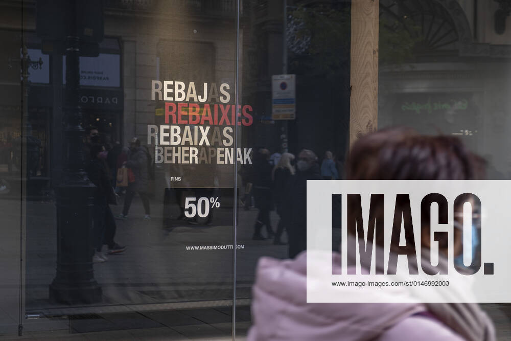 A woman wearing a facemask walks past a store window advertising up to 50% discount on winter sales..Despite the strong increase in contagions from the new Omicron variants, Barcelona fully enters the winter sales with entry to establishments restricted to a capacity of 70% Barcelona Spain - ZUMAs197 20220109_zaa_s197_114