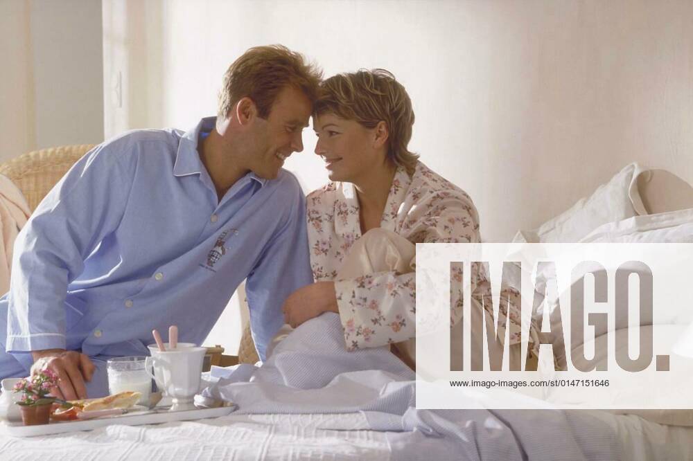 Portrait,interior,half-figure,young blonde couple in pajamas sitting in bed during breakfast on Sunday mornings model released, Symbolfoto, 25.09.2021,