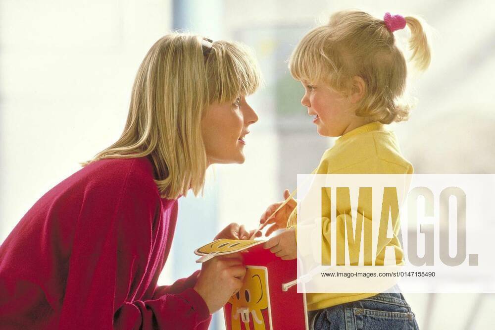 Mother with blond hair crouches in front of her blonde braided daughter,4 years old,who carries a large red-yellow kindergarten bag and speaks to her reassuringly model released, Symbolfoto, 25.09.2021,