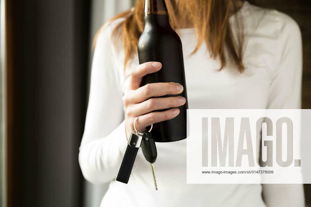 Do not drink and drive concept. Woman holding bottle of beer and car keys in hand, 26.09.2021,