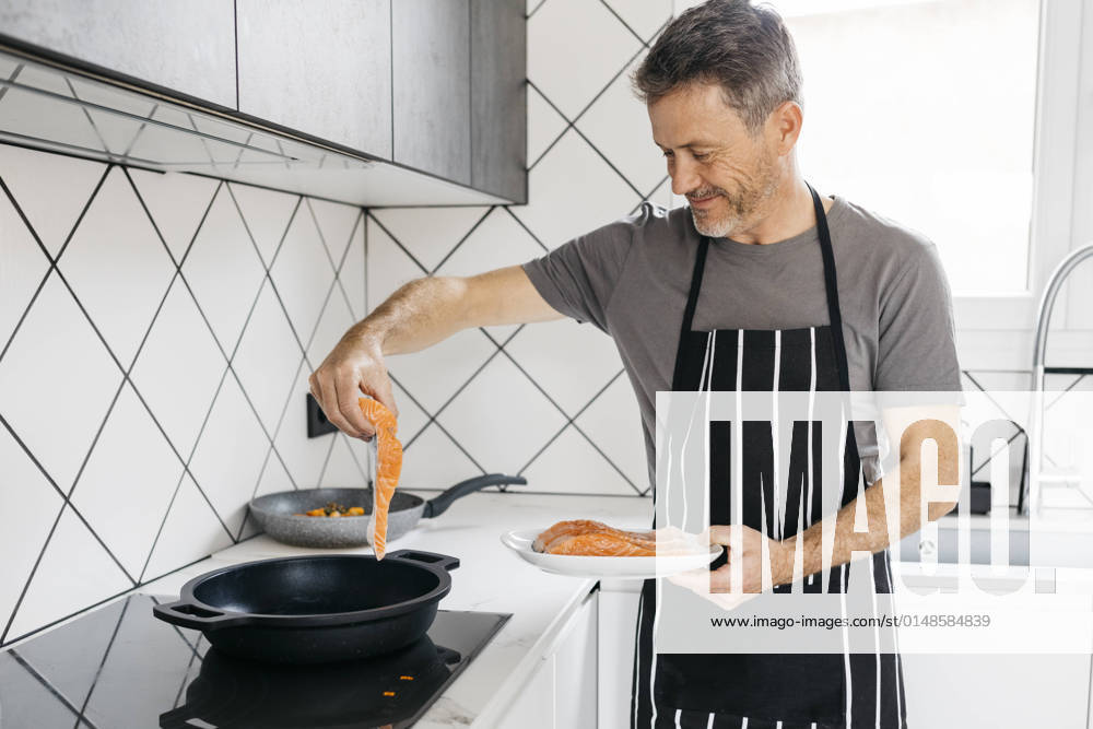 Smiling man cooking fish in kitchen at home model released property released, JRFF05250