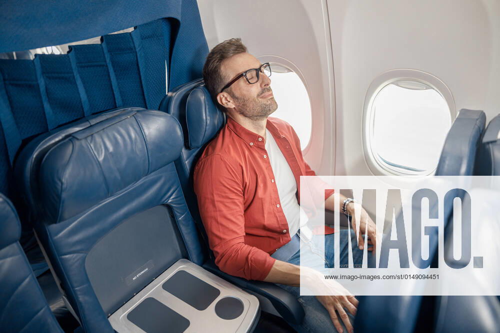 Handsome caucasian man in casual wear resting on the plane, sitting near the window Handsome caucasian man in casual wear resting on the plane, sitting near the window. Relax, travel, vacation, transportation concept