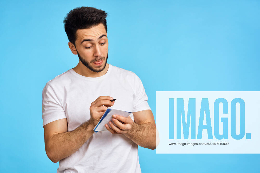 Man in white t-shirt notebook with pen student blue background man in white t-shirt notebook with pen student blue background. High quality photo