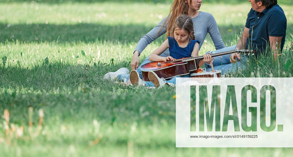 IMAGO Creative: Jahreszeit Frühling, Picknick parents with small two children on the lawn on a spring day parents with small two children on the lawn on a spring day. good time