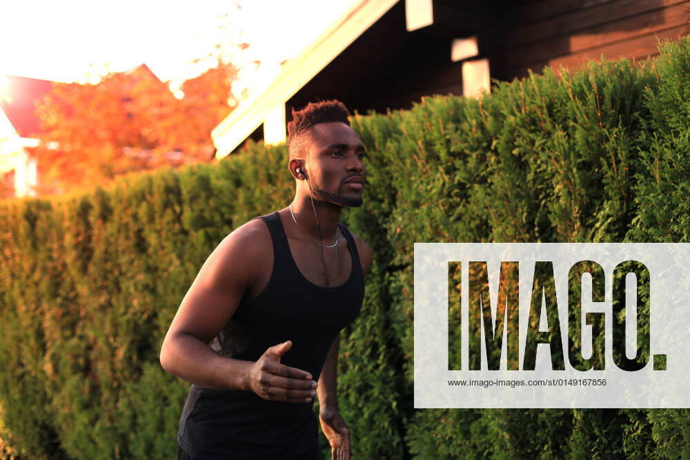 IMAGO Creative: 2022 Sport Favoriten IMAGO Creative: Neue Aussichten Full length of young African man in sports clothing jogging while exercising outdoors, at sunset or sunrise. Runner. Full length of young African man in sports clothing jogging while exercising outdoors, at sunset or sunrise. Runner.
