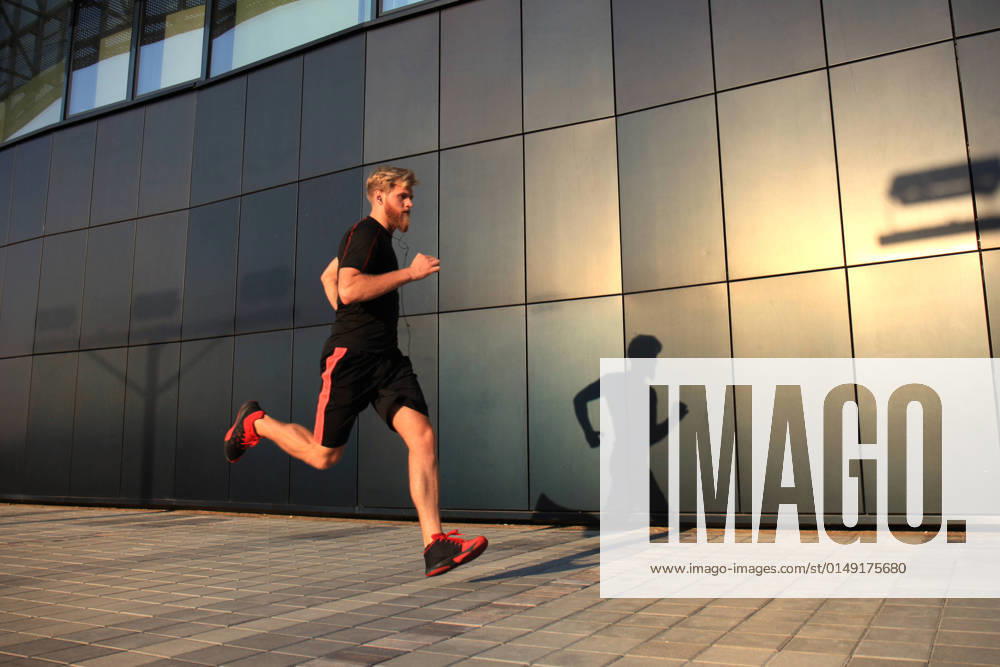 IMAGO Creative: Städte im Wandel Sporty young man running outdoors to stay healthy, at sunset or sunrise. Runner Sporty young man running outdoors to stay healthy, at sunset or sunrise. Runner