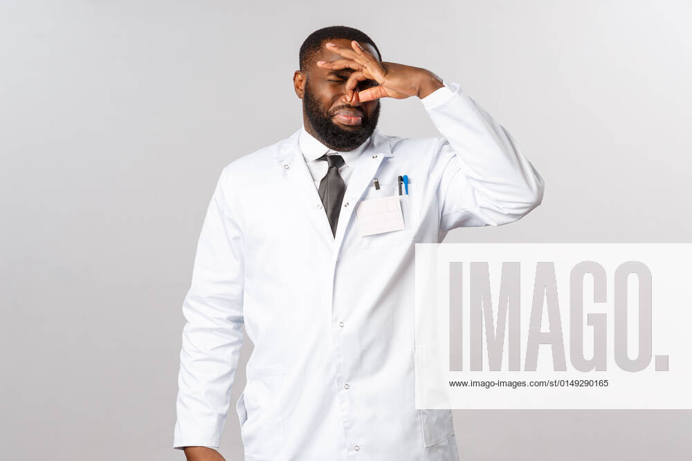 Coronavirus, covid19 and healthcare concept. Gross what that smell. Disgusted african-american male doctor shut nose and grimacing as something smelling or reek disgusting at hospital Coronavirus, covid19 and healthcare concept. Gross what that smell. Disgusted african-american male doctor shut nose and grimacing as something smelling or reek disgusting at hospital.