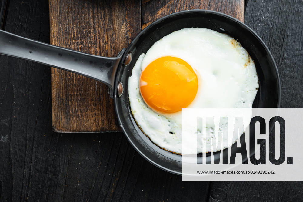 Fried Egg with ingredients in cast iron frying pan, on black wooden table background, top view flat lay Fried Egg with ingredient in cast iron frying pan, on black wooden table background, top view flat lay