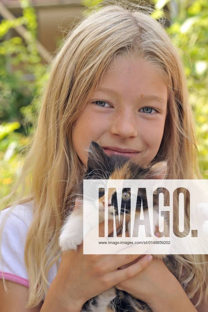 Hauskatze, Haus-Katze (Felis silvestris f. catus), kleines blondes Maedchen haelt gluecklich ein Kaetzchen in den Haenden, Portraet domestic cat, house cat (Felis silvestris f. catus), little blonde girl happily holding a kitten in her hands, portrait BLWS661199