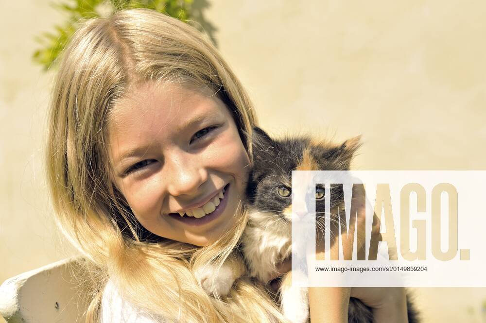 Hauskatze, Haus-Katze (Felis silvestris f. catus), kleines blondes Maedchen haelt gluecklich ein Kaetzchen in den Haenden, Portraet domestic cat, house cat (Felis silvestris f. catus), little blonde girl happily holding a kitten in her hands, portrait BLWS661202
