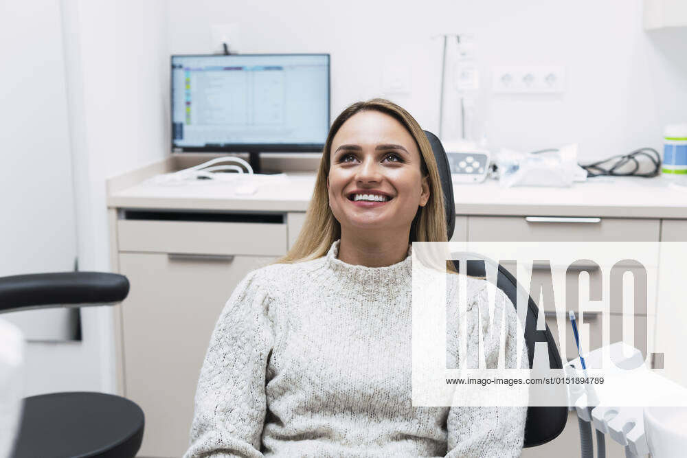 Smiling young woman sitting on dentist chair at clinic model released property released, PNAF03067