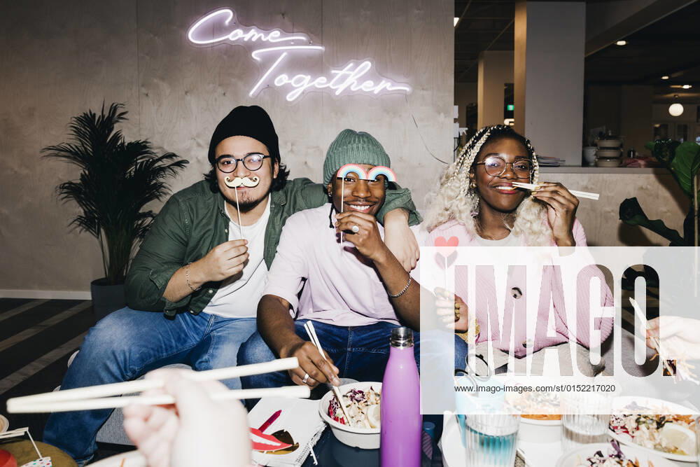 Portrait of happy multiracial male and female friends with props having food in college dorm Sweden, Stockholm, model released, property released