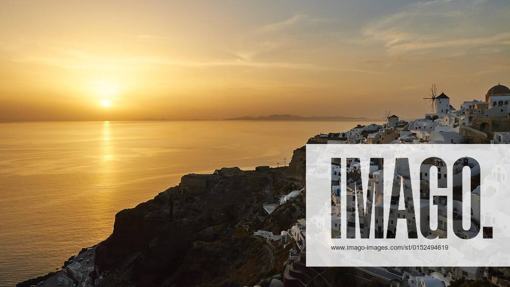 Sonnenuntergang, Himmel orangefarben, Himmel blau mit Wolken, Meer glänzt golden, Häuser von Oia, Windmühle, Oia, Insel Santorini, Kykladen, Griechenland, Europa
