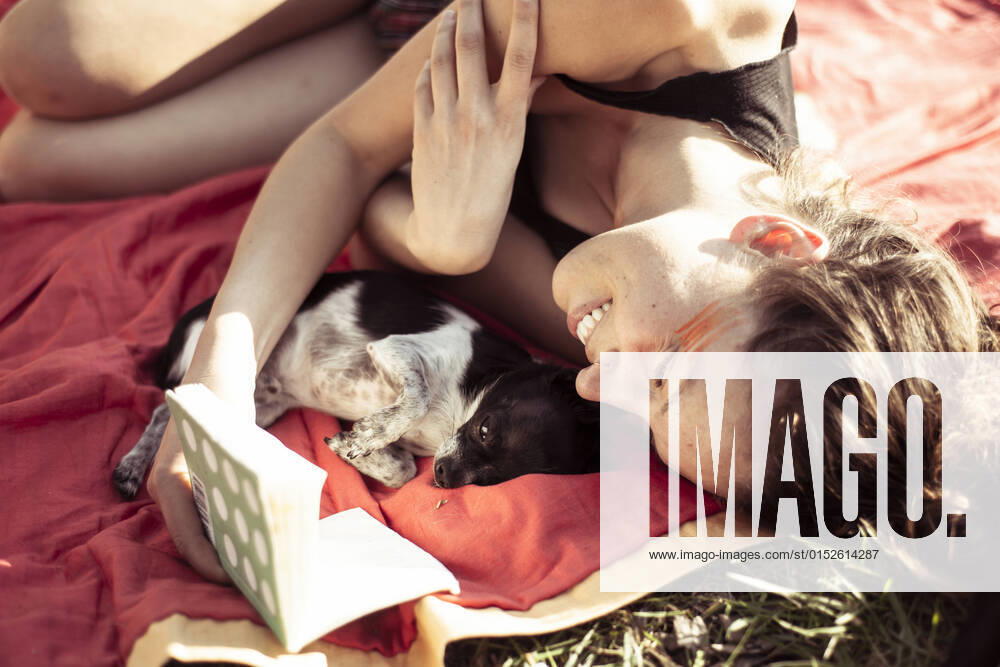 IMAGO Creative: Jahreszeit Frühling, Picknick Beautiful woman smiles and reads to tiny puppy on an afternoon picnic Grünheide (Mark), BB, Germany CR_PIDODS220304-368437-01 ,model released, Symbolfoto