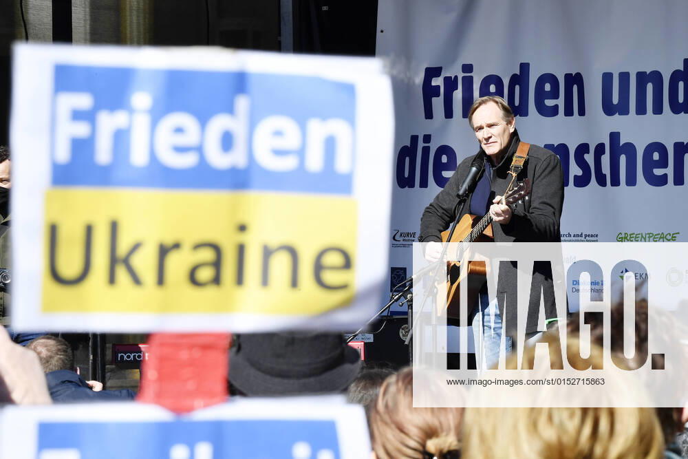 Kundgebung Demonstration Frieden und Solidarität für die Menschen in der Ukraine in Leipzig (13.03.2022) Leipzigs Oberbürgermeister Burkhard Jung bei der Demonstration gegen den Krieg in der Ukraine in Leipzig (13.03.2022) mit einer Gitarre vor einem Schild Frieden und Solidarität für die Menscen in der Ukraine. Stoppt den Krieg. Im Vordergrund in Schild mit der Aufschrift Friden Ukraine Leipzig Sachsen Deutschland Augustusplatz