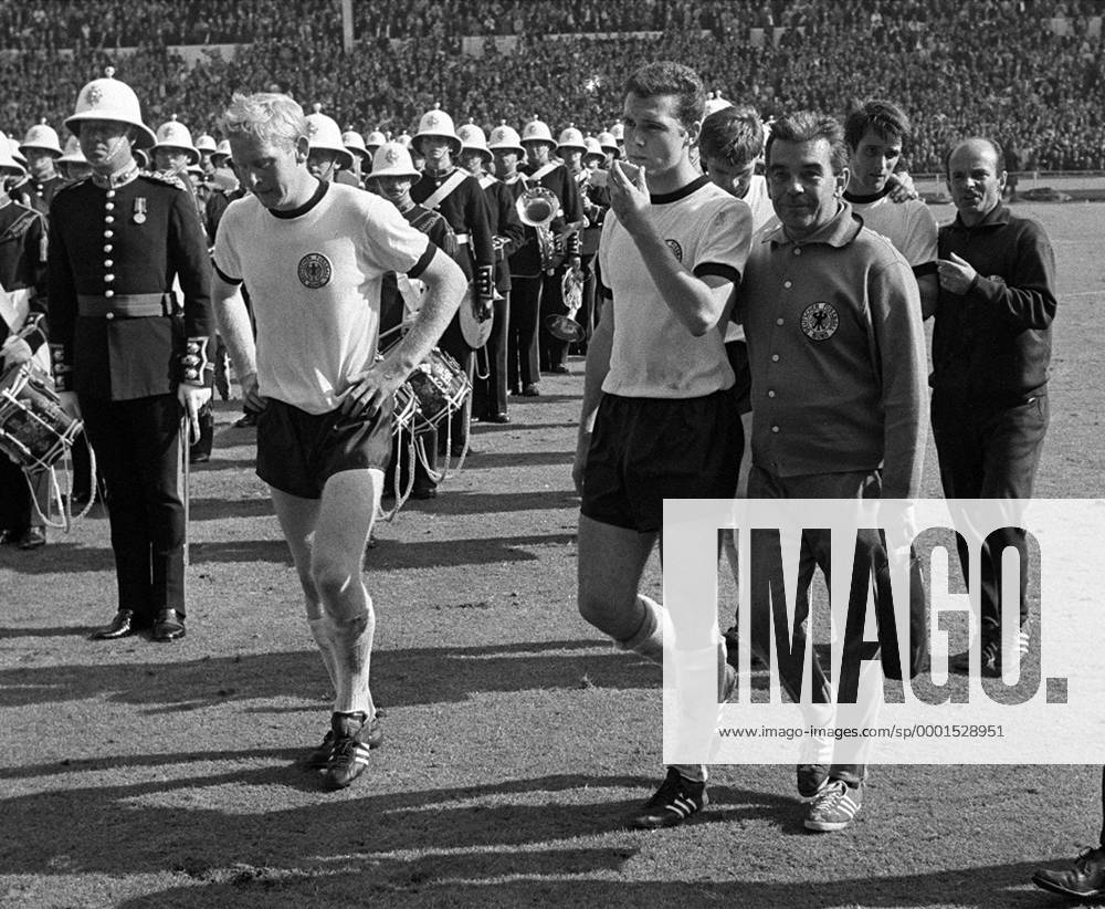 Fußball, WM 1966, Finale in Wembley, England - Deutschland 4-2 n.V. Mannschaftsarzt Hannes Schoberth (3.v.re.) und Co Trainer Dettmar Cramer (re.) führen nach der Niederlage die enttäuschten Karl Heinz Schnelliger (li.), Franz Beckenbauer (2.v.li.), Wolfgang Weber (dahinter)und Wolfgang Overath (alle BR Deutschland, 2. V. Fußball WM Herren Weltmeisterschaft 1966, Nationalmannschaft, Nationalteam, Nationaltrikot, Länderspiel, Finale, BRD Gruppe Musikkapelle, Orchester, Blasorchester, Karlheinz London, Blaskapelle, nachdenklich Enttäuschung, Nachdenklichkeit,