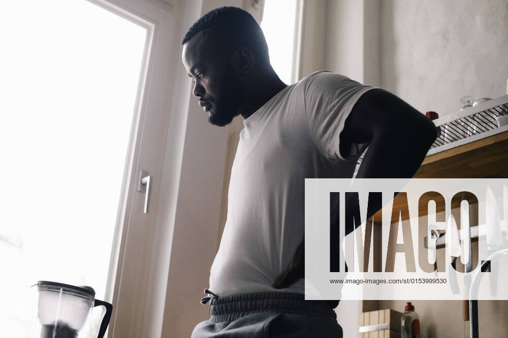Emotionally depressed lonely man standing with hand on hip in kitchen Germany, Berlin, model released, property released