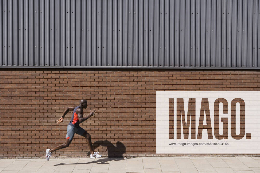 IMAGO Creative: 2022 Sport Favoriten IMAGO Creative: Sport in der Stadt Man Running Past Brick Wall, model released, , 10021806.jpg, 30s, Action, Active, Adult, African, American, Architecture, Athlete, Athletic, Bald, Black, Body, Brick, Building, City, Copyspace, Day, Energy, England, Exercise, Exterior, Fast, Fitness, Full Length, Health, Healthy, Horizontal, Leisure, London, Man, Motion, Muscular, One, Outdoors, Person, Profile, Recreation, Runner, Running, Shadow, Side View, Speed, Sport, Sportswear, Summer, Training, Urban, Wall, Workout, Young,