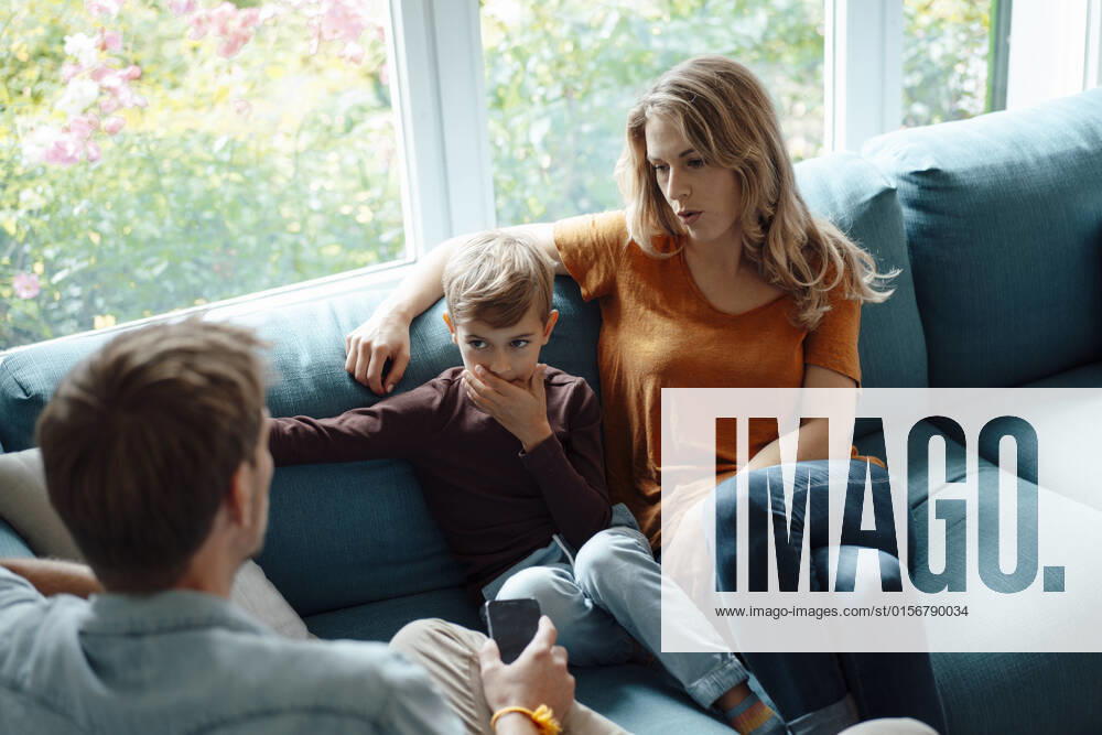Blond woman sitting by son talking with man on sofa in living room at home model released, Symbolfoto property released, JOSEF08128