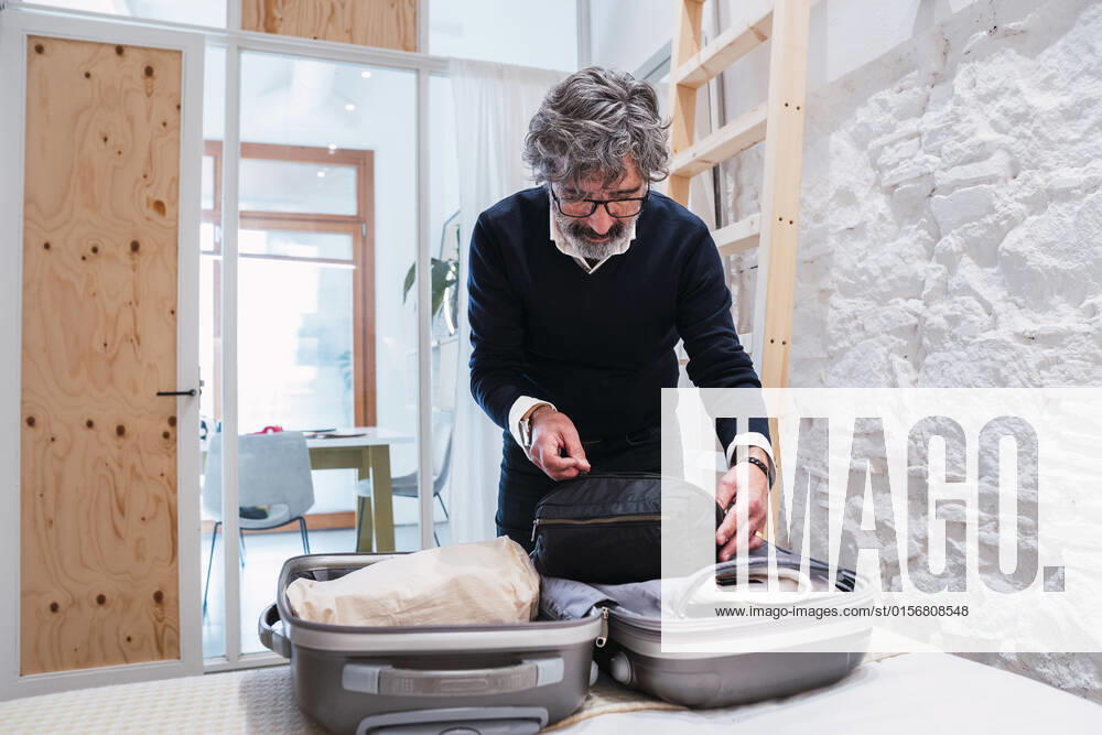 Senior freelancer packing suitcase in bedroom at home model released, Symbolfoto property released, PNAF03600