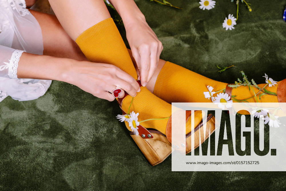 Crop anonymous bride in white elegant dress and colorful socks putting small flowers into shoes while sitting in light studio HodeiUnzueta_BrideWithFlowersAtStudio_00022.jpg