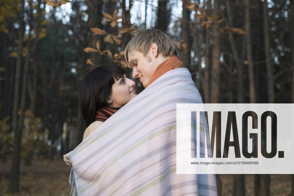 Young couple wrapped in blanket embracing in forest, model released, , 10111560.jpg, Outdoors,Standing,25-30 Years,Young Adult Man,Whites,Leisure Activities,Relaxation,Enjoyment,Half-Length,Smiling,people,Side View,Togetherness,Happiness,Affection,Hugging,Love,Embracing,Face To Face,Young Adult Woman,Young Couple,Looking In Eyes,Romance,Intimacy,Forest,Desire,Park,Sensuality,Heterosexual Couple,Autumn,Leaves,Leaf,Trees,Wrapped,Warm Clothing,Wrapped Up,2 People, Russia