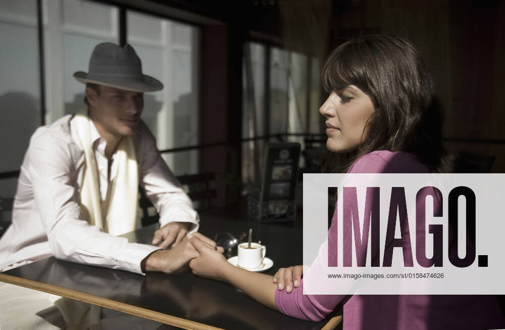 Young couple sit holding hands in cafe, model released, , 10131914.jpg, Young Adult,Indoors,Portrait,Side View,Sitting,Woman,Man,Hat,Holding Hands,20-25 Years,Young Couple,Road Trip,half length,Caucasian,Sunlight,Cafe,inside,Sunny,Relationship Difficulties,expresso,parting,Communication Problems, South Africa