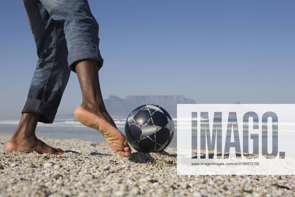 IMAGO Creative: Sommer Sport - Strand Young Man Playing Soccer On Beach, model released, , 10115932.jpg, Active, Activity, Adult, African, American, Ball, Barefoot, Beach, Black, Blue, Closeup, Coastline, Copyspace, Denim, Exercise, Feet, Fitness, Foot, Football, Health, Horizontal, Jeans, Legs, Leisure, Lowsection, Man, Mountain, Nature, Ocean, One, Outdoors, Person, Playing, Practising, Recreation, Rolled Up, Sand, Sea, Shore, Side View, Sky, Soccer, South Africa, Sport, Summer, Sunny, Training, Vitality, Young, 30s,