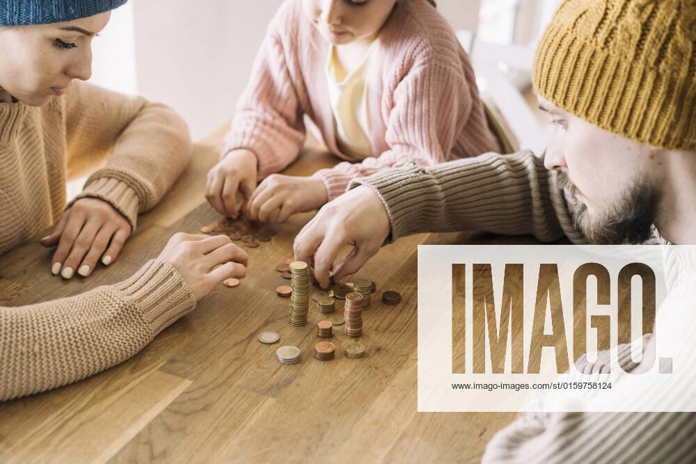 Poor family with winter hats sitting at table counting coins model released, Symbolfoto property released, KMKF01841
