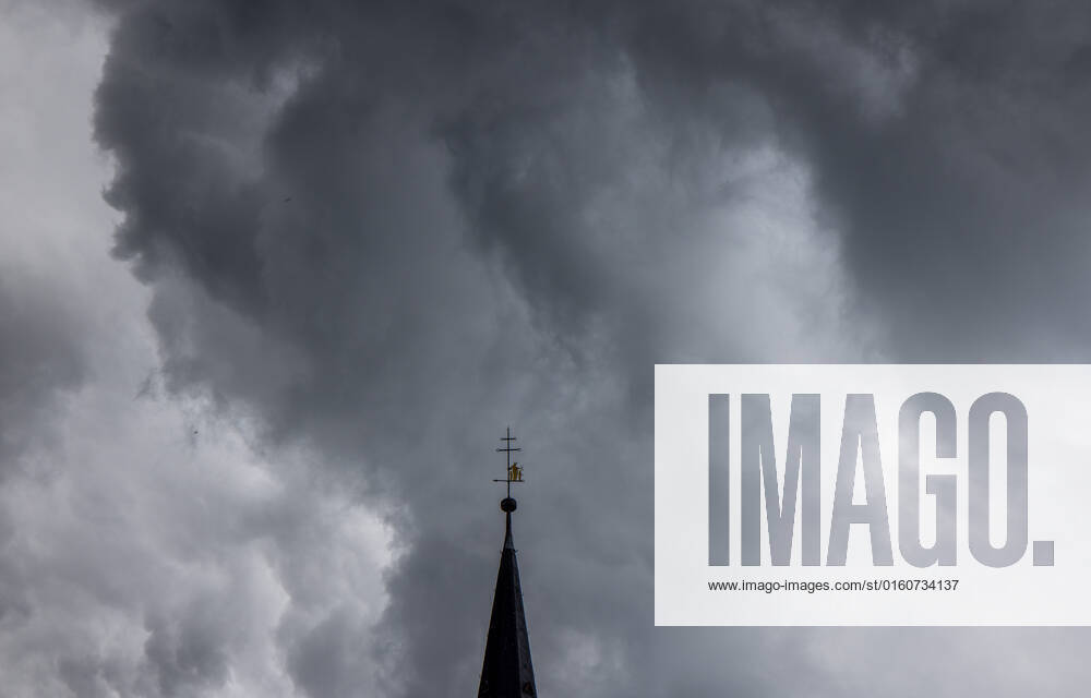 Dunkle Wolken über dem Kirchturm Dunkle Wolken eines Schauers sind am Abend am Himmel über dem Kirchturm der katholischen Kirche St.-Ursula in Oberursel zu sehen., Oberursel Hessen Deutschland