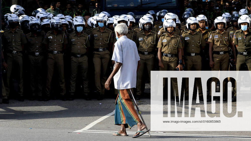 Economic Crisis In Sri Lanka A Sri Lankan man walks watched by police officers in front of Ministry of Education during a protest at Colombo, Sri Lanka. 10 June 2022. Colombo Sri Lanka