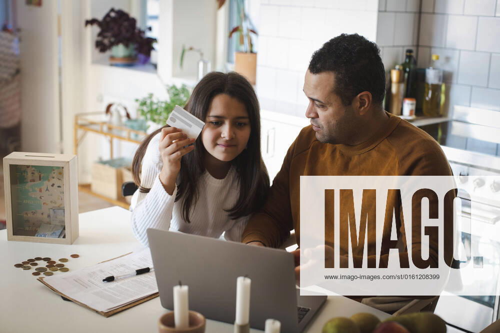 Father teaching online shopping to daughter on laptop at home Sweden, Stockholm, model released, property released