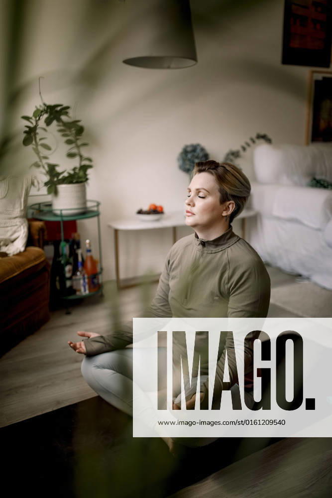 IMAGO Creative, Lifestyle, Tik Tok-Trend thatgirl Lesbian woman with eyes closed practicing yoga at home Sweden, Stockholm, model released, property released