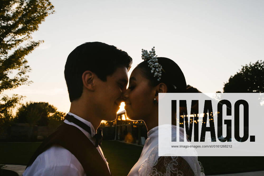 IMAGO Creative: 2022 Favoriten IMAGO Creative: Momentaufnahmen Multiracial bride and groom snuggle and kiss in backlight Provo, Utah, United States CR_WVNP220506-971687-01 ,model released, Symbolfoto