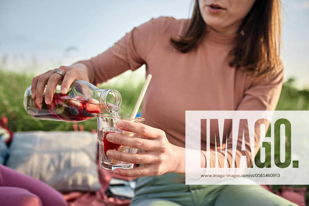 Young woman pouring infused water in glass at field on weekend model released, Symbolfoto, ZEDF04562