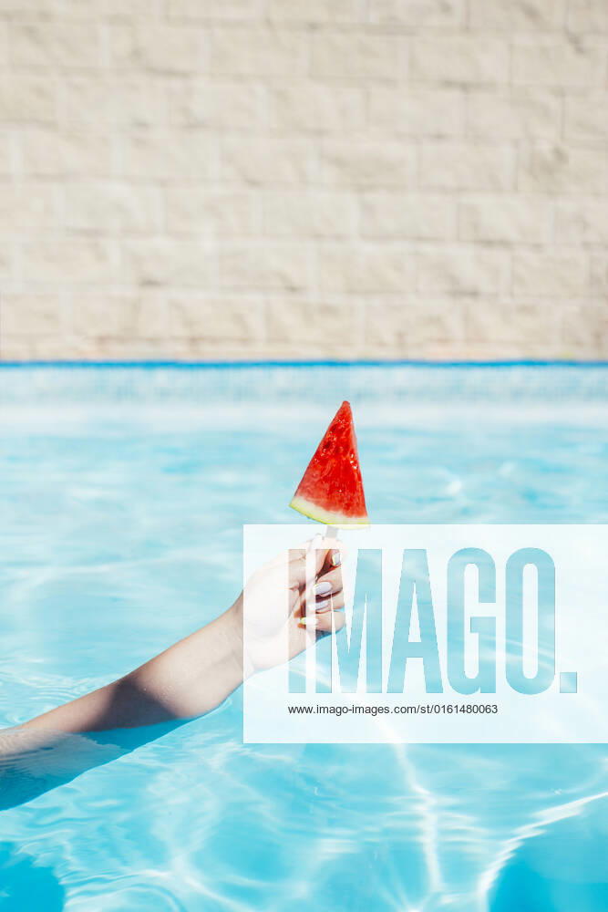 Hand of woman holding watermelon slice with popsicle stick in swimming pool model released, Symbolfoto, EGHF00449